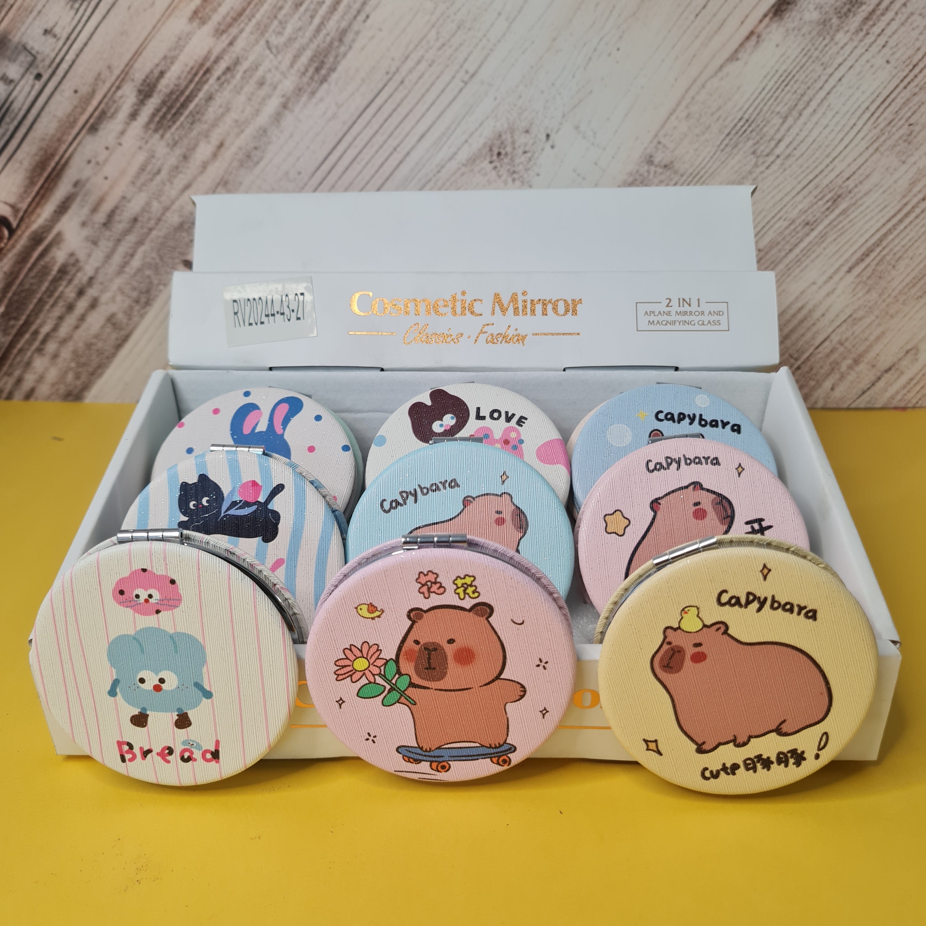 Set of cartoon-themed cosmetic mirrors with a box on a wooden surface.